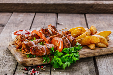 meat skewers with potatoes on the board