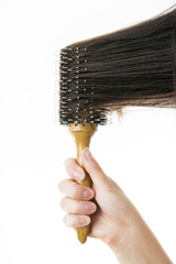 Comb in a female hand on a white background