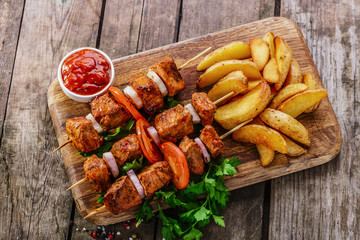meat skewers with potatoes on the board