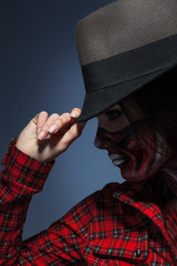 Profile portrait of woman in halloween art on face and hat