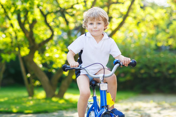 Fototapeta na wymiar Happy preschool kid boy having fun with riding his bicycle
