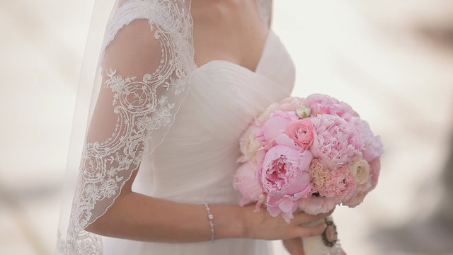 Bride standing with gorgeous bridal bouquet of pink peonies