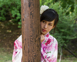 Asian woman in kimono behind wooden pillar
