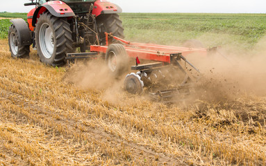 Tractor cultivating wheat stubble field, crop residue.