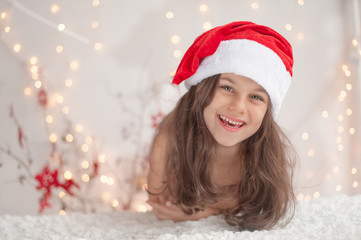 A cute smiling girl in a Santa hat