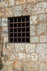 Fototapeta na wymiar Window with rusty iron bars, stone wall