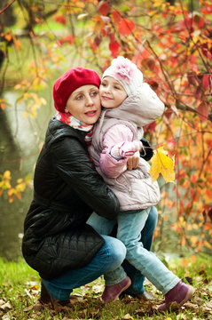 girl and mother are hiding behind a tree in the autumn park