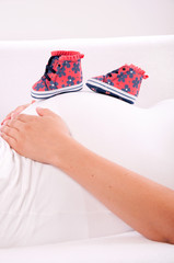 Small shoes for the unborn baby in the belly of pregnant woman