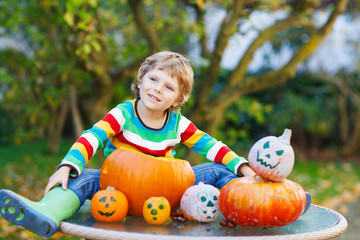 Little kid boy making jack-o-lantern for halloween in autumn gar