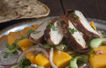 Grilled chicken breast with fresh mango salad and naan bread