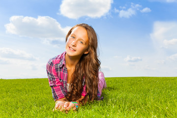 Beautiful girl laying on green grass and smiling