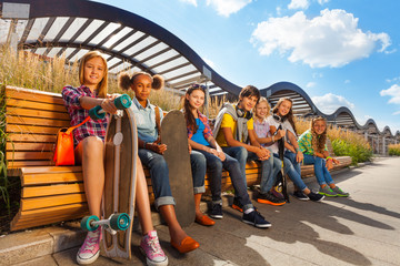View of happy kids who sit on wooden bench