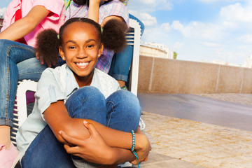 African smiling girl sitting on stoned road