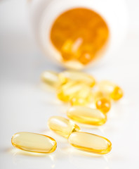 shiny yellow vitamin e fish oil capsule spilling out of pill bot