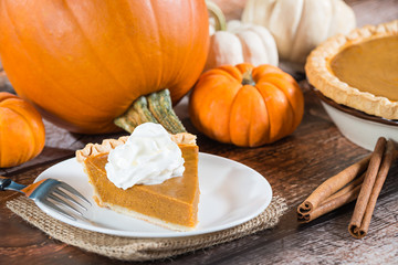 Slice of a pumpkin pie and pumpkins on the background