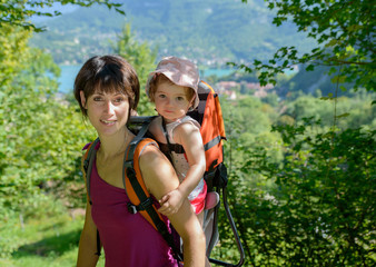 a little girl in a baby carrier walks with his mom