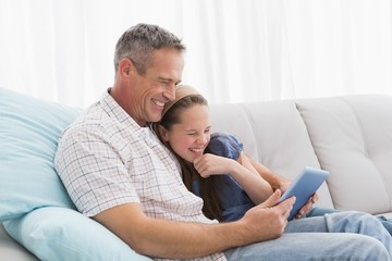 Father with daughter relaxing on the couch using laptop