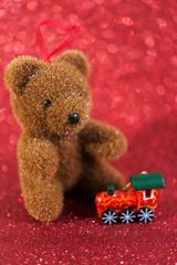 xmas toys - cute bear and wooden small train. Greeting card concept. christmas decoration on red glitter blur background