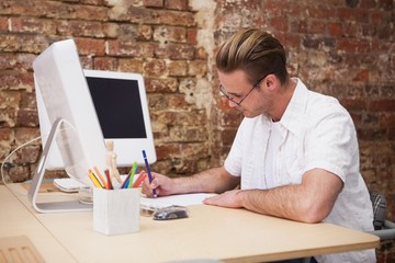 Handsome happy man using computer taking notes