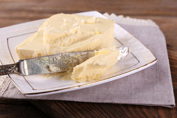 Fresh butter on plate, on wooden background