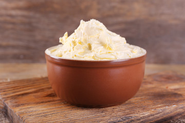 Fresh homemade butter in bowl, on wooden background
