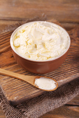 Fresh homemade butter in bowl, on wooden background