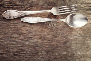 Metal spoon and fork on wooden background