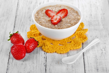Tasty oatmeal with strawberry on table close-up