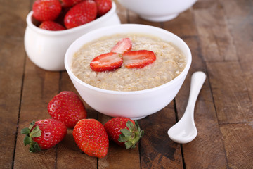 Tasty oatmeal with strawberry on table close-up