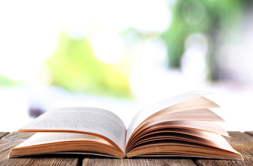 Open book on wooden table on natural background