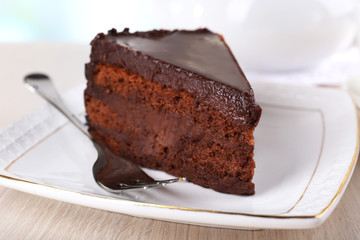 Piece of chocolate cake on saucer on teapot background