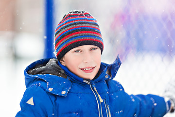 Funny cheerful boy in jacket playing outdoors in winter 