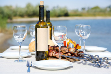Picnic table with skewers and wine, close-up
