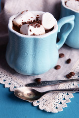 Cups of coffee with marshmallow and napkin on wooden table