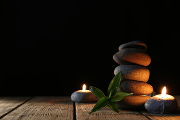 Spa stones, candles on wooden table on dark background