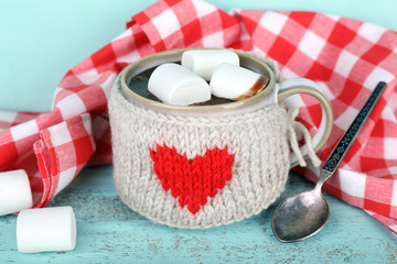Cup of tasty hot cocoa, on wooden table, on color background