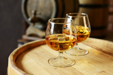 Glasses of brandy in cellar with old barrels