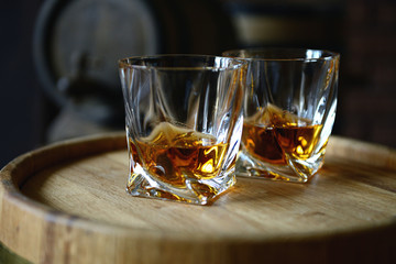 Glasses of brandy in cellar with old barrels