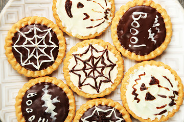 Tasty Halloween cookies on plate, on wooden table