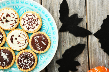 Tasty Halloween cookies on plate, on wooden table