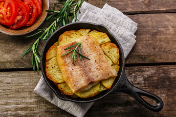 Baked fish fillets with potatoes in a frying pan