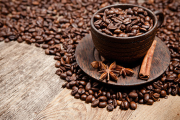 Coffee cup with coffee beans on wooden table.