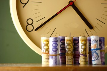 An analog clock and rolls of paper money