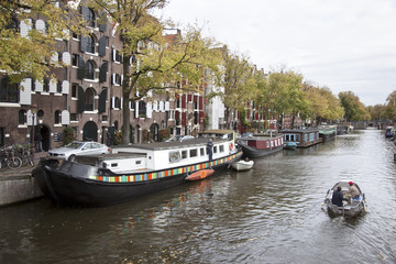 Fototapeta na wymiar small boat passing houseboats in brouwersgracht