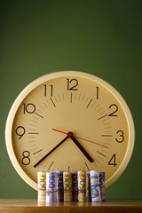 An analog clock and rolls of paper money