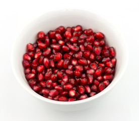 Bowl of ripe pomegranate seeds against white
