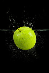 green apple dropped into water with splash isolated on black