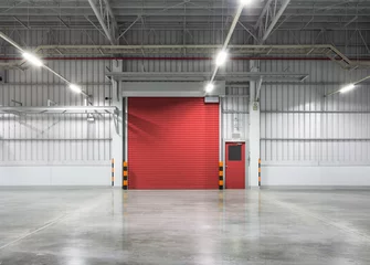 Wall murals Industrial building Roller door or roller shutter inside factory, warehouse or industrial building. Modern interior design with polished concrete floor and empty space for product display or industry background.