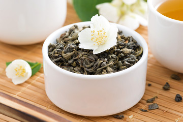 dry green tea with jasmine and cups of tea, close-up
