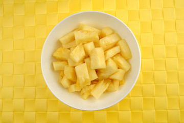 Bowl of juicy pineapples against a textured background